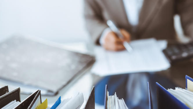 Vīrietis sēž pie galda ar dokumentiem un tos paraksta. ilutratīvs attēls