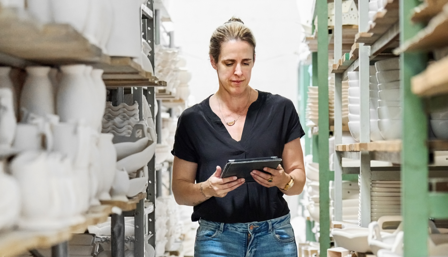 Cilvēks trauku noliktavā ar planšeti rokās.